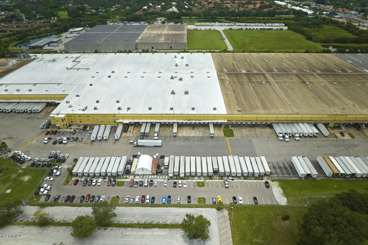 Logistics-Company-Truck-Warehouse A logistics company warehouse location showing many trucks parked outside