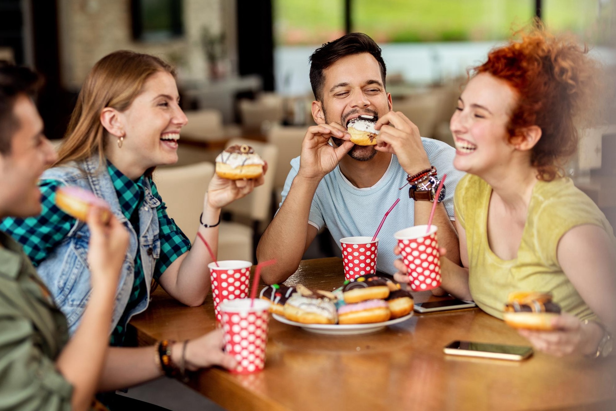 A happy group of friends eating donuts at a fast food restaurant